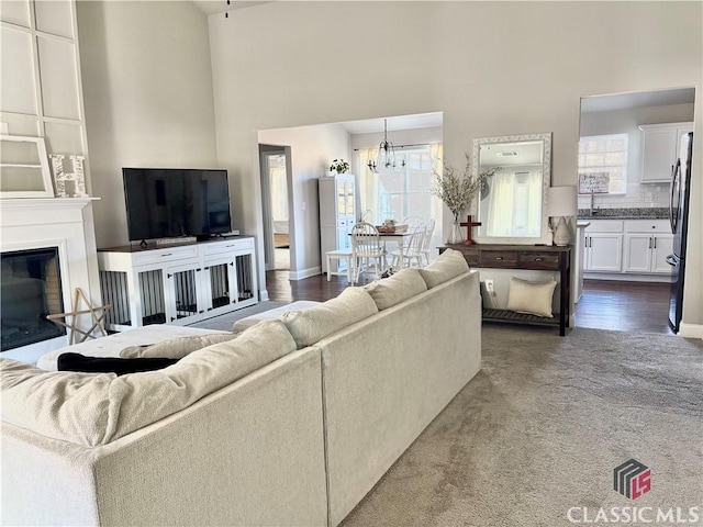 living room featuring dark colored carpet, a chandelier, a high ceiling, and sink