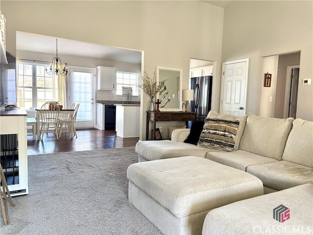 living room with dark wood-type flooring, an inviting chandelier, a high ceiling, and sink