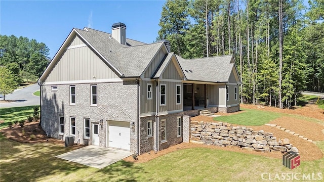 rear view of house with central AC unit, a garage, and a lawn