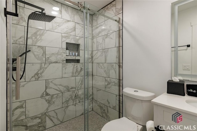 bathroom featuring toilet, a shower with door, and vanity