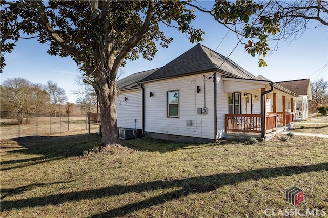 view of side of property featuring a yard, a porch, and central AC