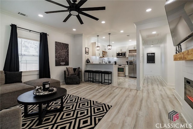 living room featuring light hardwood / wood-style floors, crown molding, and ceiling fan