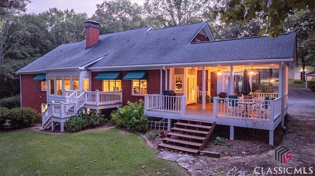 back house at dusk with a deck and a lawn