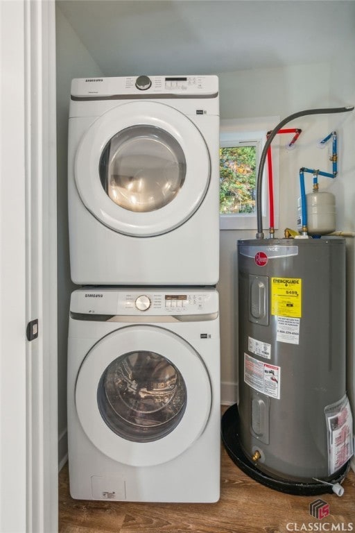 clothes washing area featuring stacked washer and clothes dryer, wood-type flooring, and electric water heater