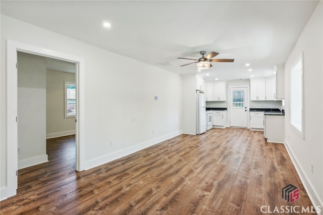 unfurnished living room featuring ceiling fan, sink, and wood-type flooring