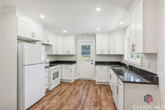 kitchen with sink, hardwood / wood-style flooring, white cabinets, white appliances, and dark stone countertops