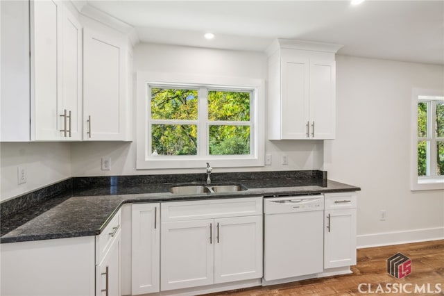 kitchen with white dishwasher, hardwood / wood-style flooring, sink, white cabinets, and dark stone counters