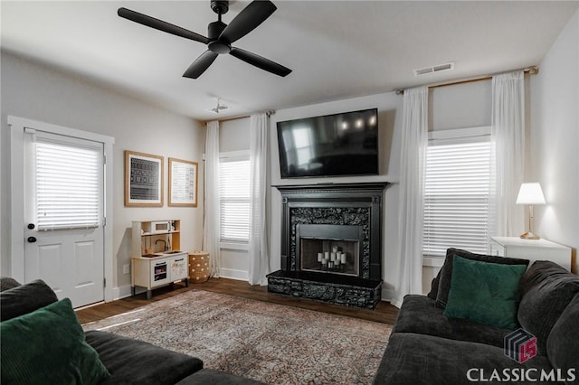 living room featuring ceiling fan, hardwood / wood-style flooring, a healthy amount of sunlight, and a high end fireplace