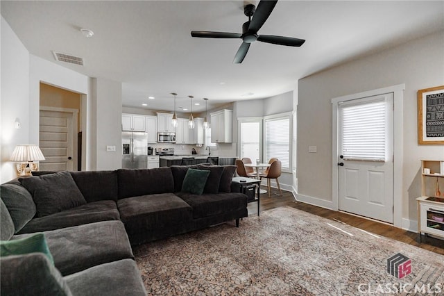 living room featuring sink, dark wood-type flooring, and ceiling fan