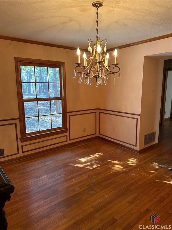 unfurnished dining area featuring a textured ceiling, dark hardwood / wood-style flooring, and ornamental molding