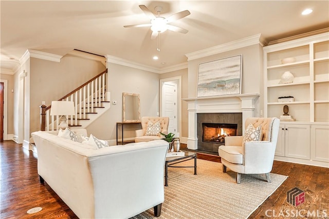 living room featuring crown molding, a fireplace, dark hardwood / wood-style flooring, and ceiling fan