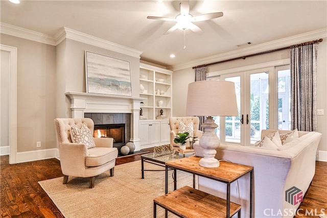 living room featuring dark wood-type flooring, ornamental molding, a healthy amount of sunlight, and a tiled fireplace