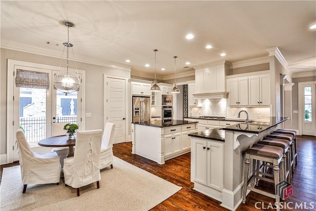 kitchen with white cabinetry, hanging light fixtures, and a center island with sink