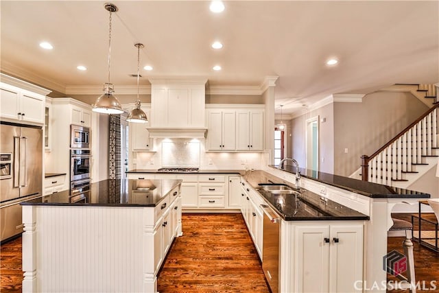 kitchen featuring pendant lighting, sink, stainless steel appliances, and a center island