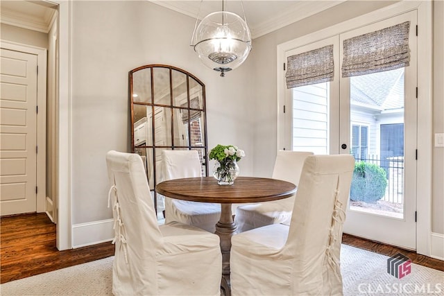 dining area featuring ornamental molding, dark wood-type flooring, and an inviting chandelier