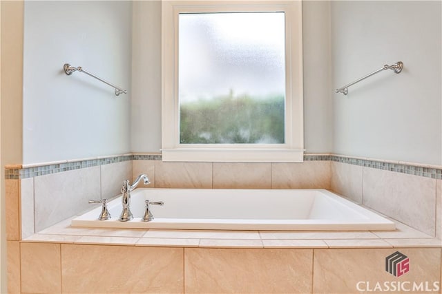 bathroom featuring a healthy amount of sunlight and tiled bath