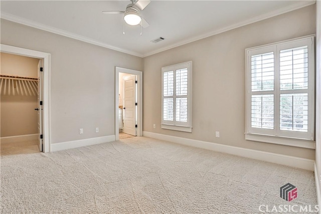 unfurnished bedroom featuring ceiling fan, ornamental molding, a spacious closet, light colored carpet, and a closet