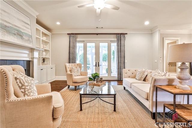 living room with built in features, french doors, ceiling fan, crown molding, and light hardwood / wood-style flooring