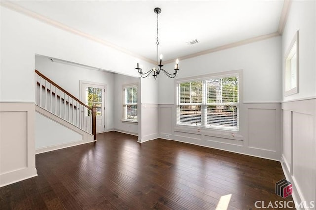 unfurnished dining area featuring crown molding, plenty of natural light, dark wood-type flooring, and a notable chandelier