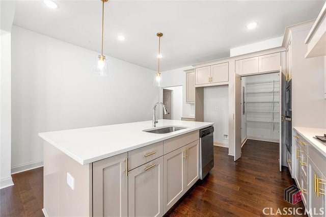 kitchen featuring pendant lighting, dishwasher, sink, dark wood-type flooring, and a kitchen island with sink