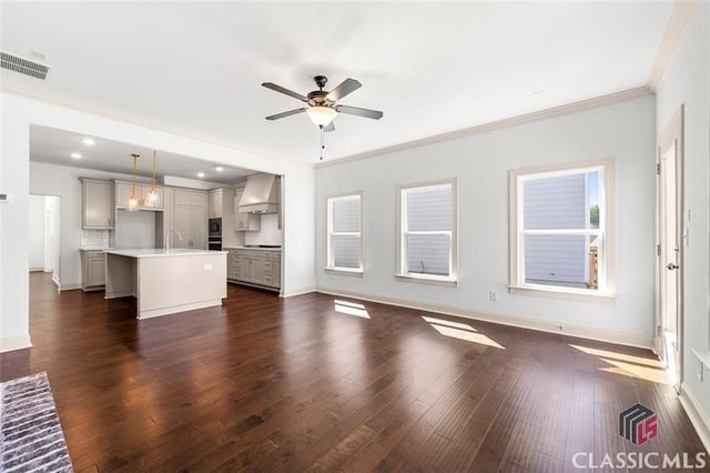 unfurnished living room with sink, dark wood-type flooring, ceiling fan, and ornamental molding