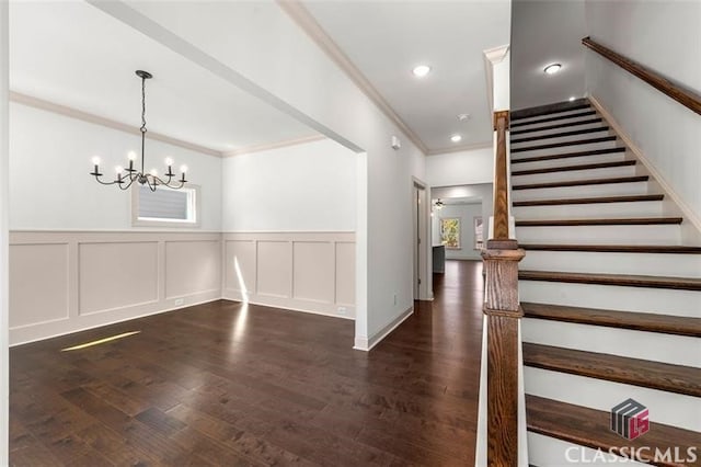 foyer featuring crown molding, a wealth of natural light, a notable chandelier, and dark hardwood / wood-style flooring