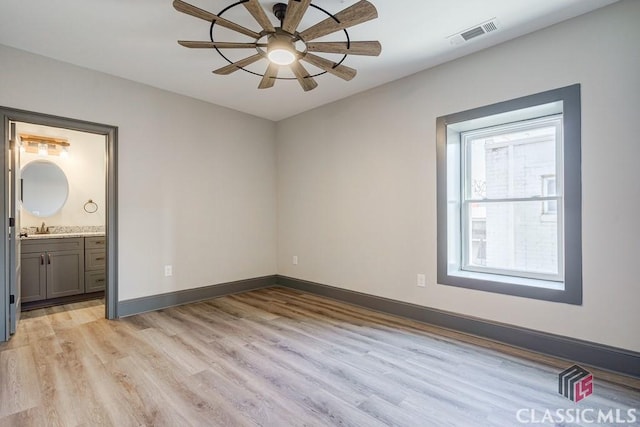 unfurnished bedroom featuring a spacious closet, light hardwood / wood-style flooring, a closet, and ceiling fan