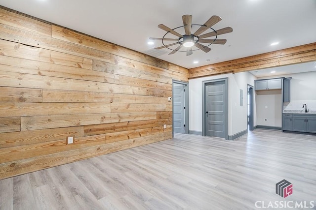 empty room featuring crown molding, ceiling fan, wooden walls, and light hardwood / wood-style floors