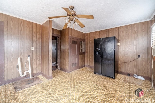 interior space with ceiling fan, crown molding, a textured ceiling, and wood walls