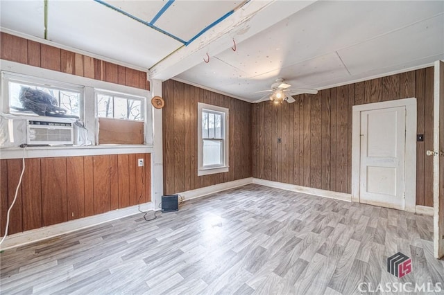 spare room featuring ceiling fan, cooling unit, wooden walls, and light hardwood / wood-style flooring