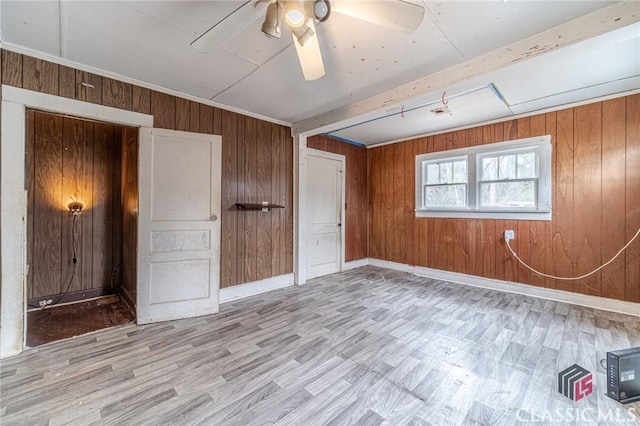 unfurnished bedroom with ceiling fan, light hardwood / wood-style flooring, and wood walls