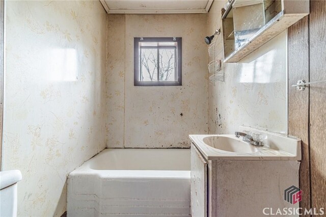 bathroom with crown molding, vanity, and a bathtub