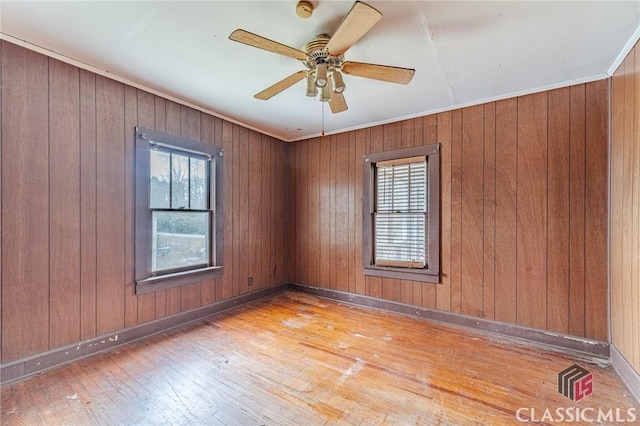 unfurnished room featuring ceiling fan, ornamental molding, a wealth of natural light, and light wood-type flooring