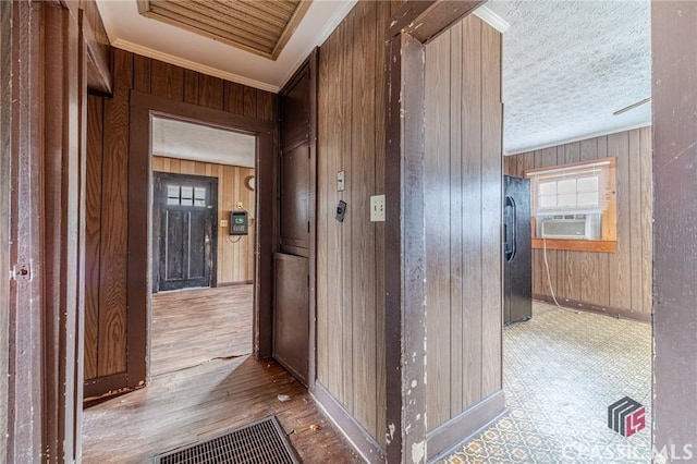 hall featuring wood walls, a textured ceiling, light wood-type flooring, ornamental molding, and cooling unit