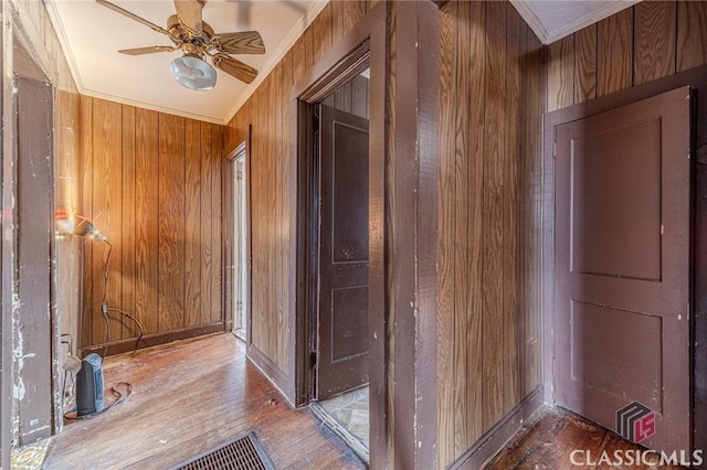 hall featuring hardwood / wood-style flooring, ornamental molding, and wood walls