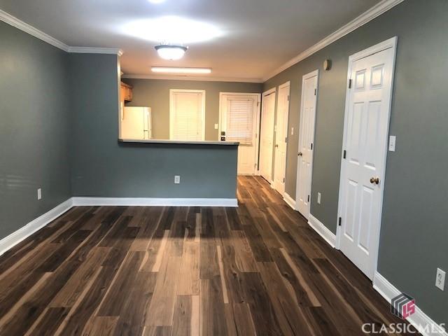 spare room with crown molding and dark wood-type flooring