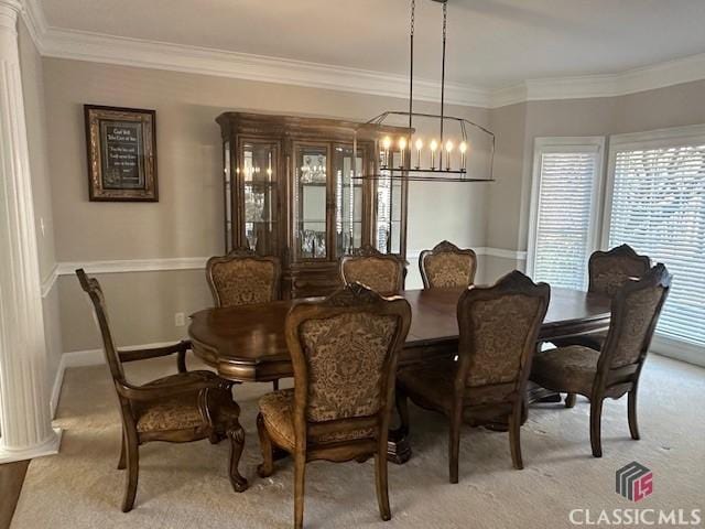 dining area with light carpet, a notable chandelier, ornamental molding, and decorative columns