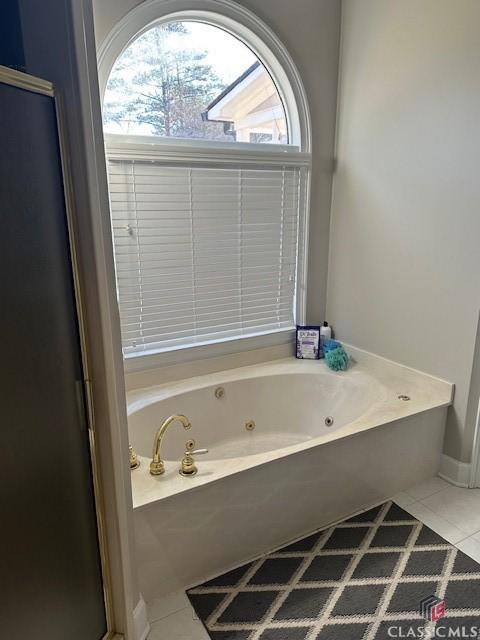 bathroom with tile patterned flooring, a wealth of natural light, and a bathing tub