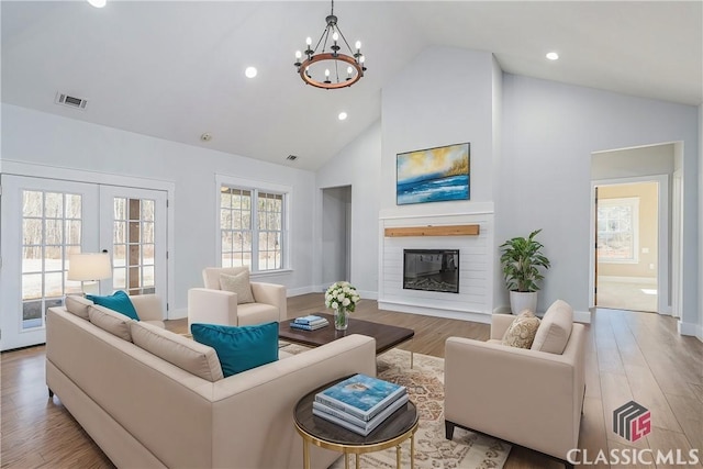 living room with french doors, a notable chandelier, high vaulted ceiling, and light wood-type flooring