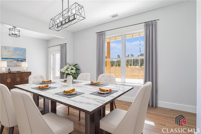 dining space with a notable chandelier, light wood-type flooring, and a wealth of natural light