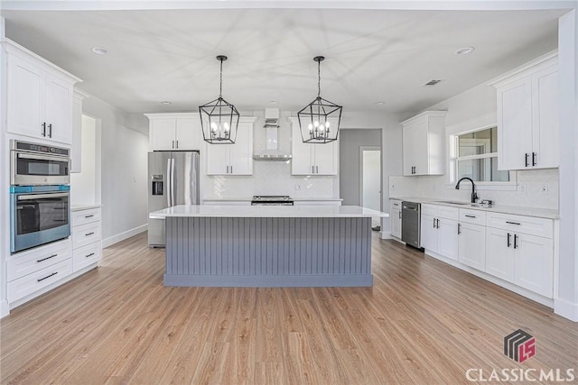 kitchen with a center island, wall chimney exhaust hood, white cabinets, and appliances with stainless steel finishes