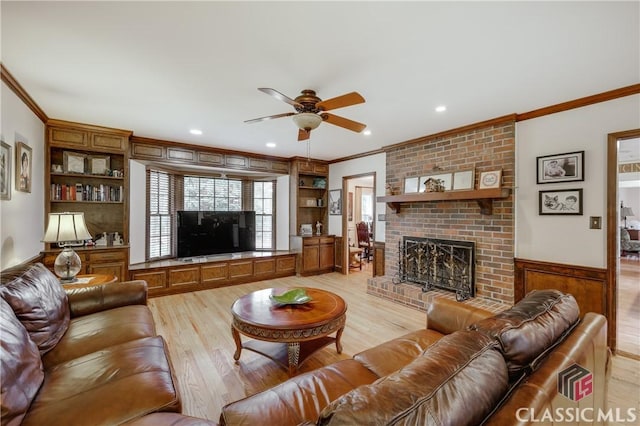 living room with built in shelves, ornamental molding, light hardwood / wood-style floors, and a brick fireplace