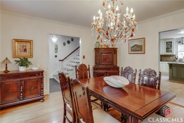 dining area with an inviting chandelier, ornamental molding, and light wood-type flooring