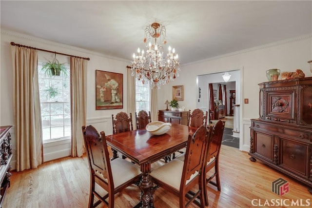 dining area with ornamental molding, a chandelier, and light wood-type flooring