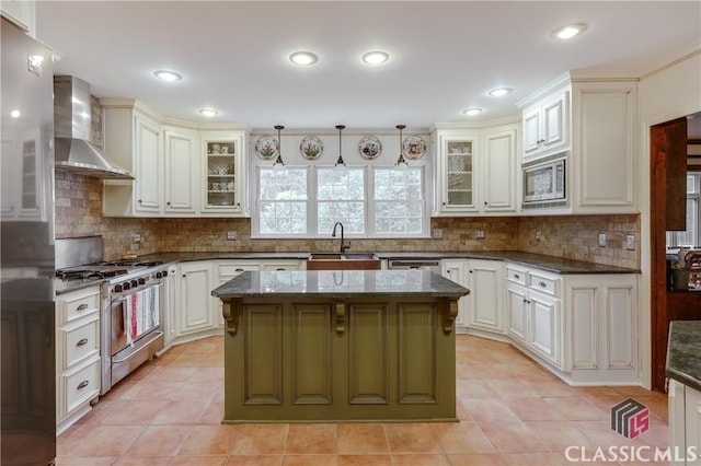 kitchen with a kitchen island, decorative light fixtures, sink, stainless steel appliances, and wall chimney range hood