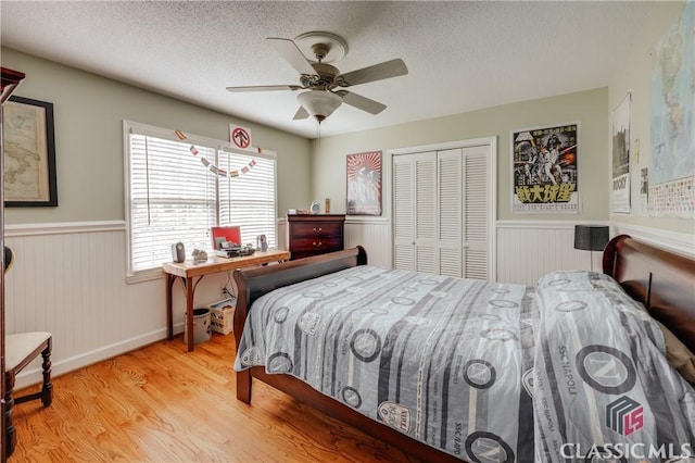 bedroom featuring a textured ceiling, light hardwood / wood-style flooring, a closet, and ceiling fan