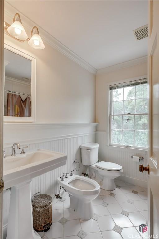 bathroom featuring a bidet, crown molding, tile patterned floors, and toilet