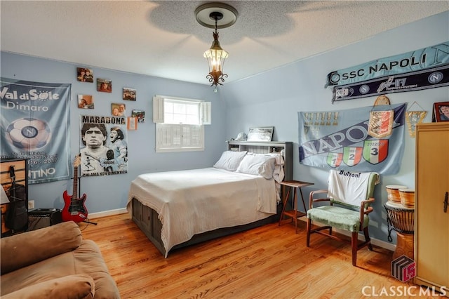 bedroom featuring lofted ceiling, a textured ceiling, and light wood-type flooring