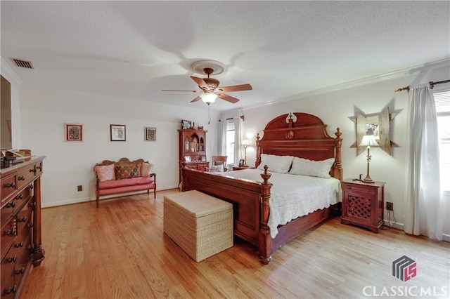 bedroom with crown molding, a textured ceiling, ceiling fan, and light hardwood / wood-style flooring