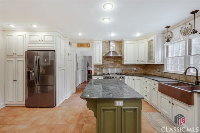 kitchen featuring stainless steel refrigerator with ice dispenser, wall chimney exhaust hood, range, a kitchen island, and pendant lighting